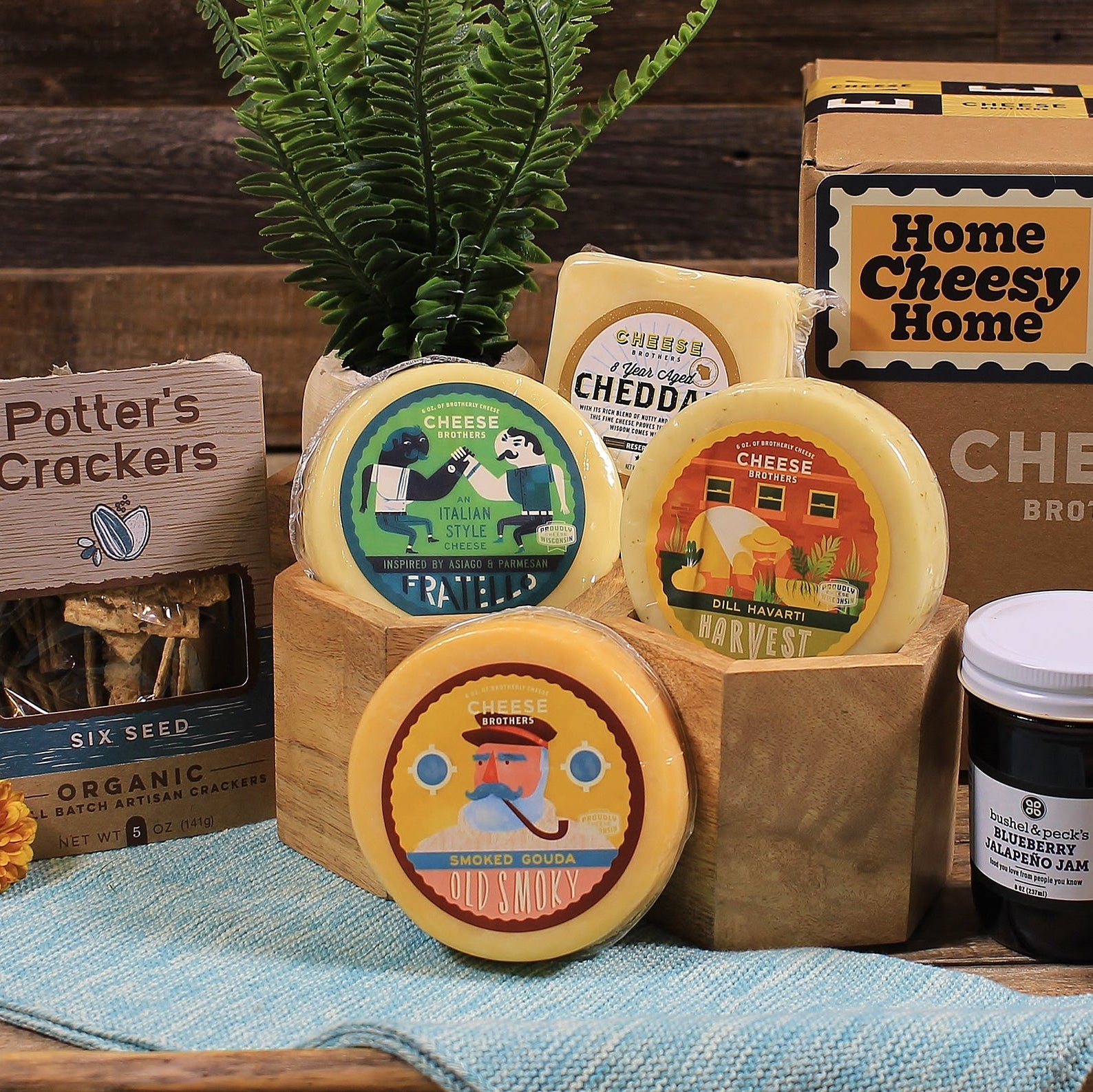 Collection of cheese wheels and a jar with 'Home Cheesy Home' branding on a wooden surface.