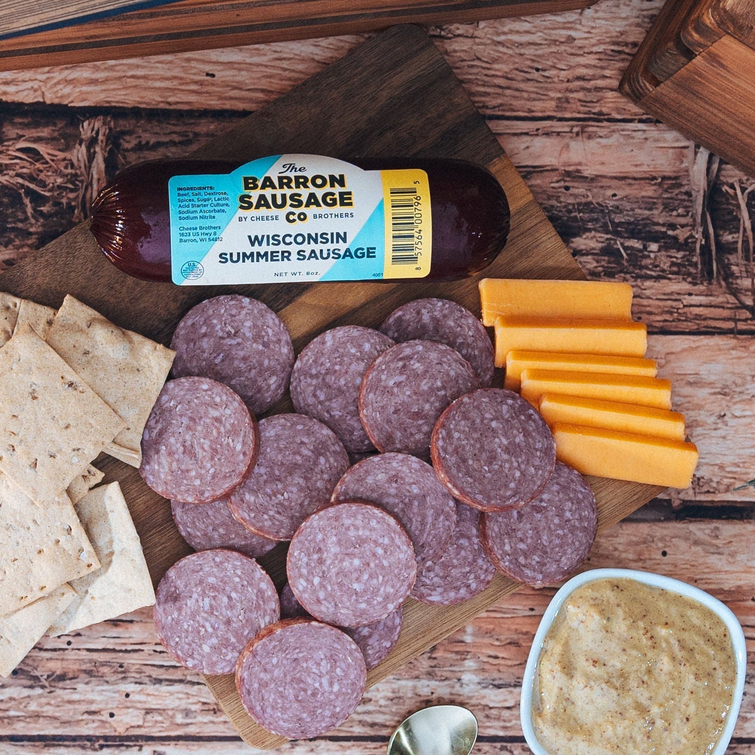 Barron Sausage Wisconsin Summer Sausage with crackers, cheese, and mustard on a wooden surface