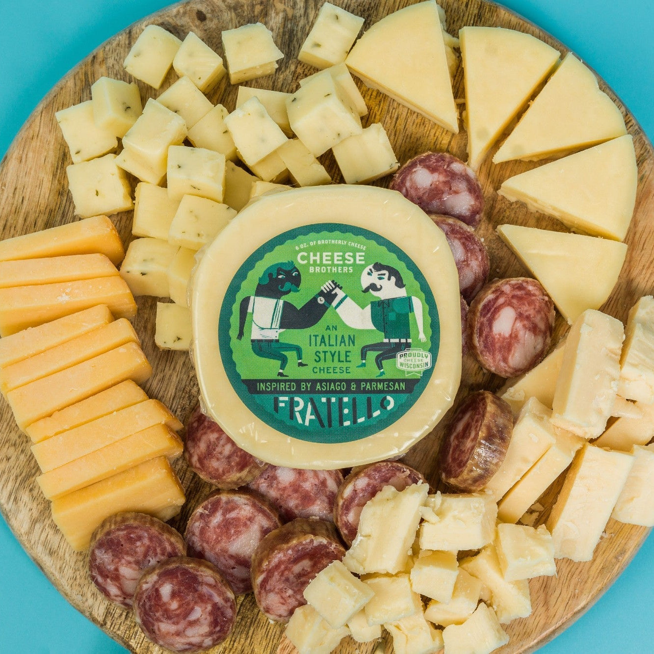 Assorted cheeses and sausages on a wooden board with a branded cheese container.