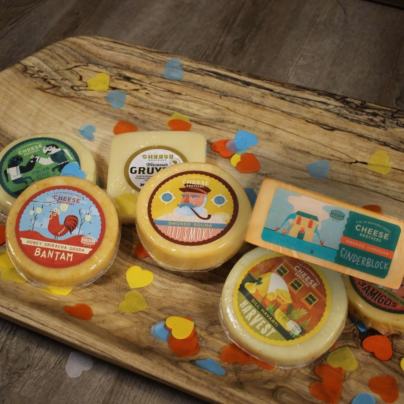 Assorted cheeses on a wooden board with colorful labels