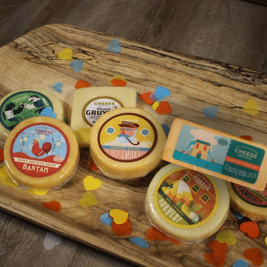 Assorted cheeses on a wooden board with colorful labels