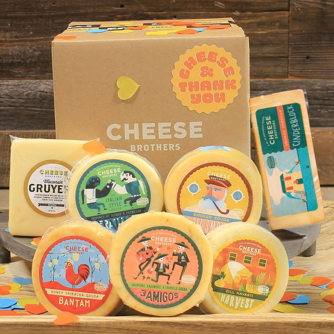 Collection of cheese wheels with colorful labels on a wooden board against a rustic wooden background.