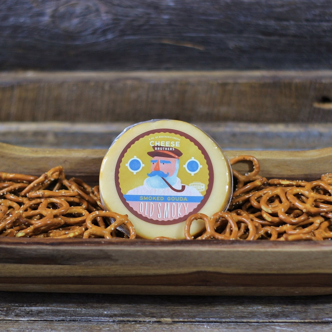 Pretzels in a wooden bowl with a decorative cookie on top, set against a rustic wooden background.