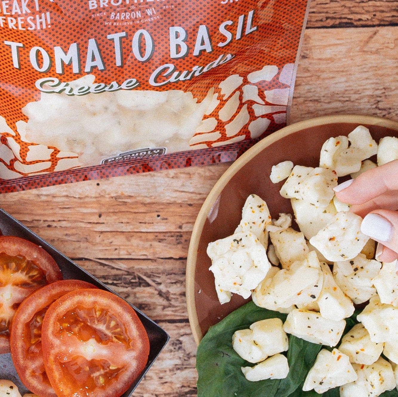 Tomato basil cheese curds packaging with a bowl of popcorn and tomatoes on a wooden surface